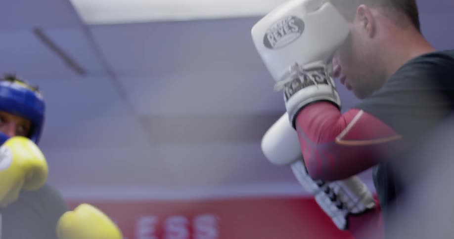 Two men wearing boxing gloves practice boxing jabs