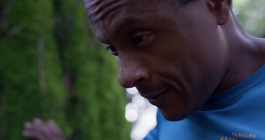 A man is looking down by the forest