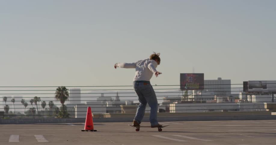 A man jumps over a cone on a skateboard
