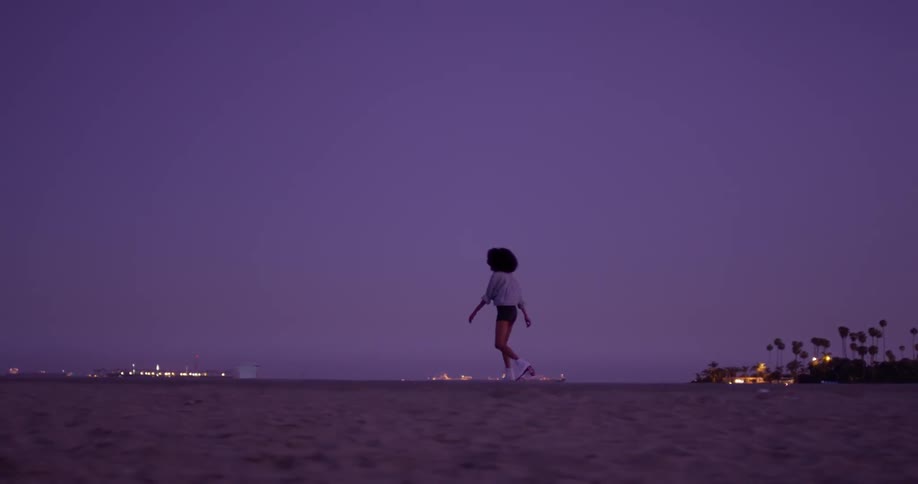 A woman is rollerskating on the beach at dawn