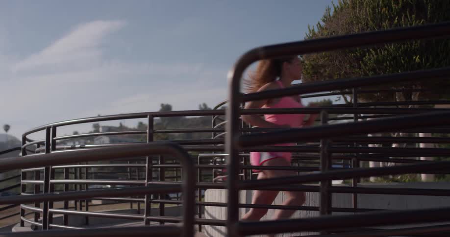 A woman jogs down a ramp in a city
