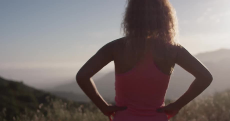 A woman looks out from atop a mountain