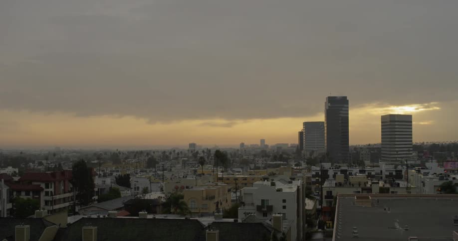 Clouds float over city buildings at sunset