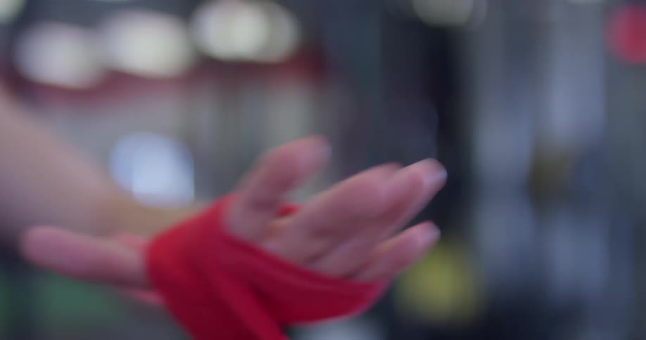 A woman wraps athletic tape around her hand in a gym