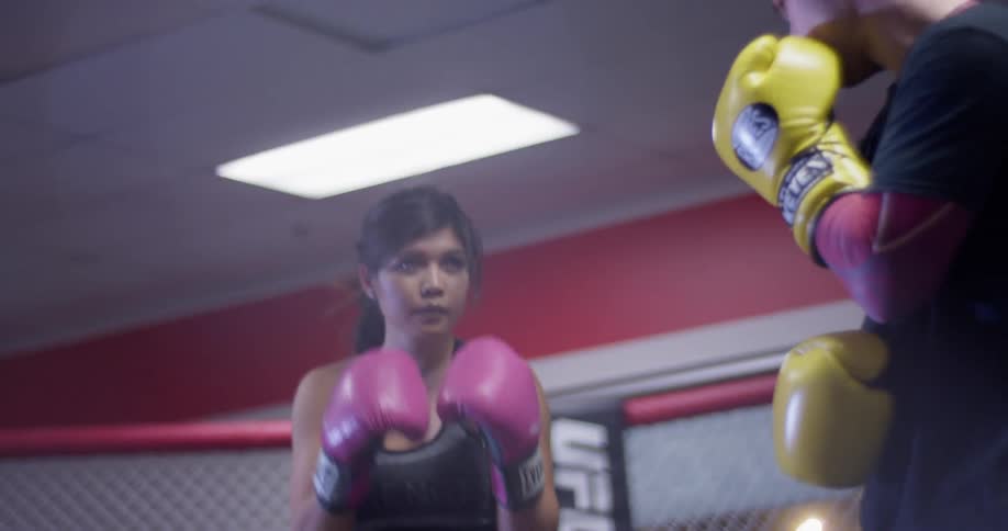 A woman spars with a man with boxing gloves