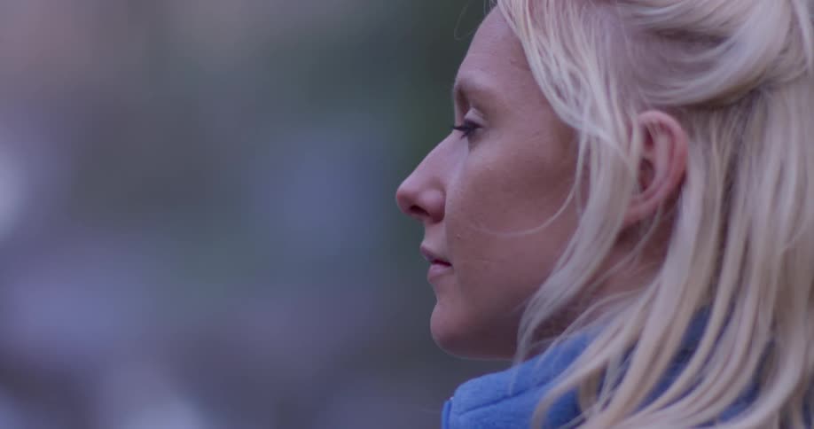 A woman stands outside at sunset