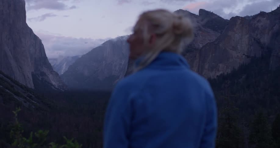A woman hikes in mountains at dusk