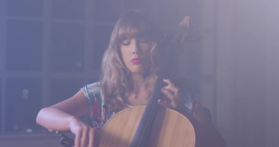 Woman plays a cello by a window with her eyes closed