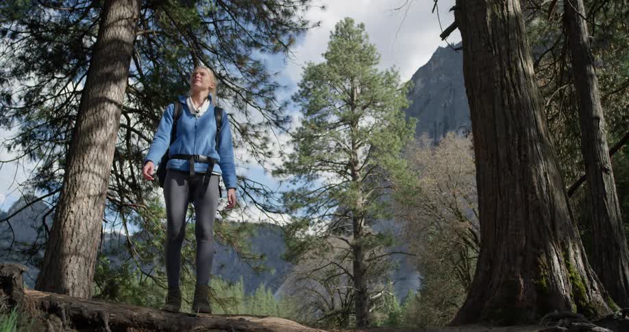 Woman walks through the woods near a mountain