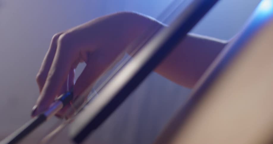 Person pushes a bow over cello strings
