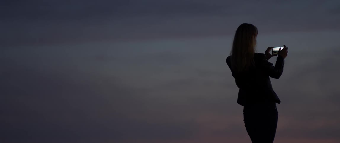 Woman takes a picture at sunset