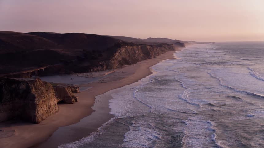 The waves slowly hit the shore at sunset