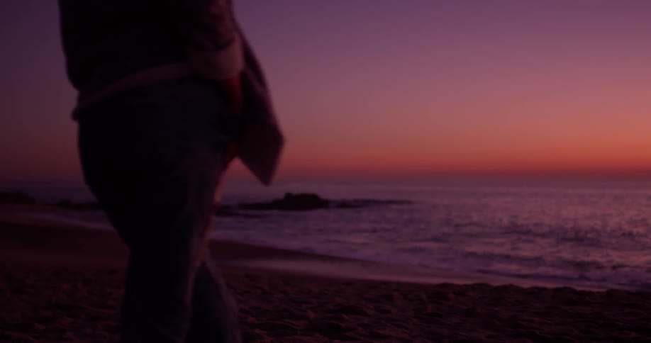 Person stands on the beach at sunset