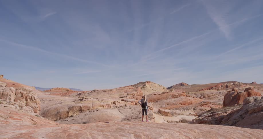 Woman stands looking out at rocky hilly land
