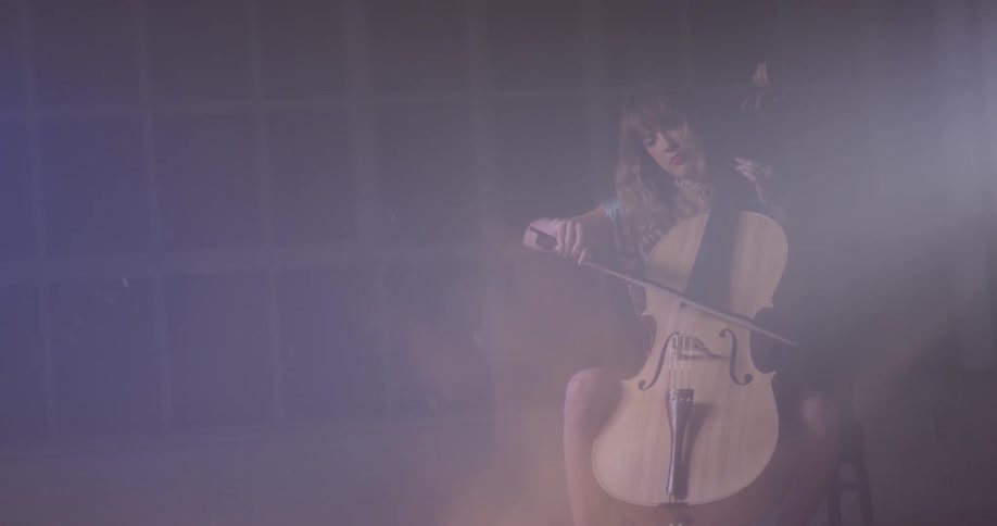 Woman plays the cello next to a large window in an empty room