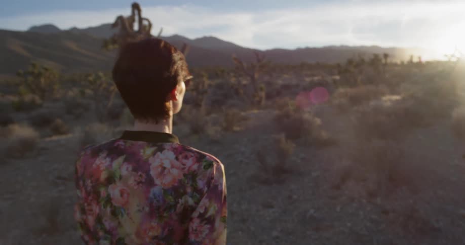 Woman walks in the desert at sunset