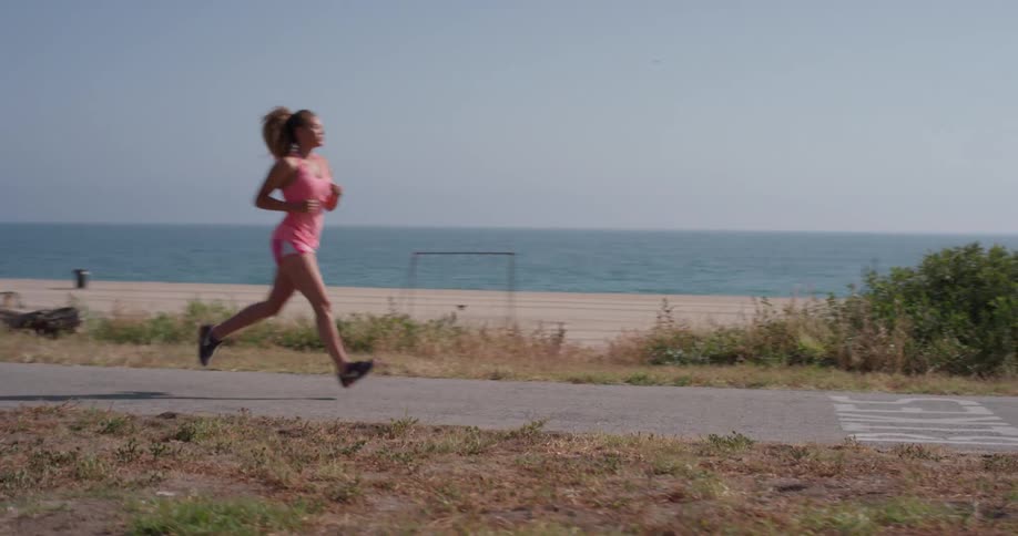 A woman jogs on a path near the beach