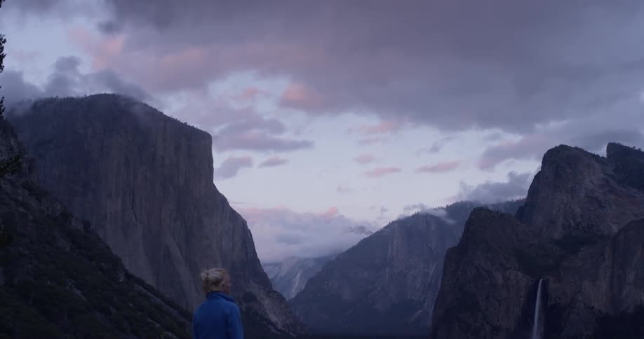 Woman walks outside near mountains on a cloudy evening