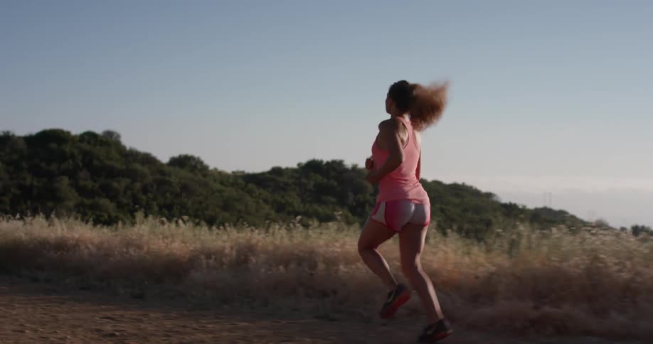 A woman runs on the field on top of the hill