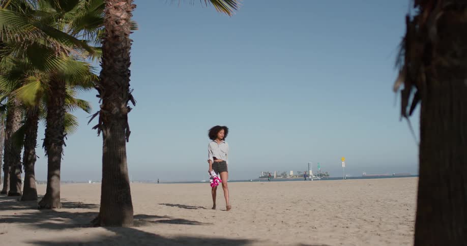 A woman carries her roller skates in the sand