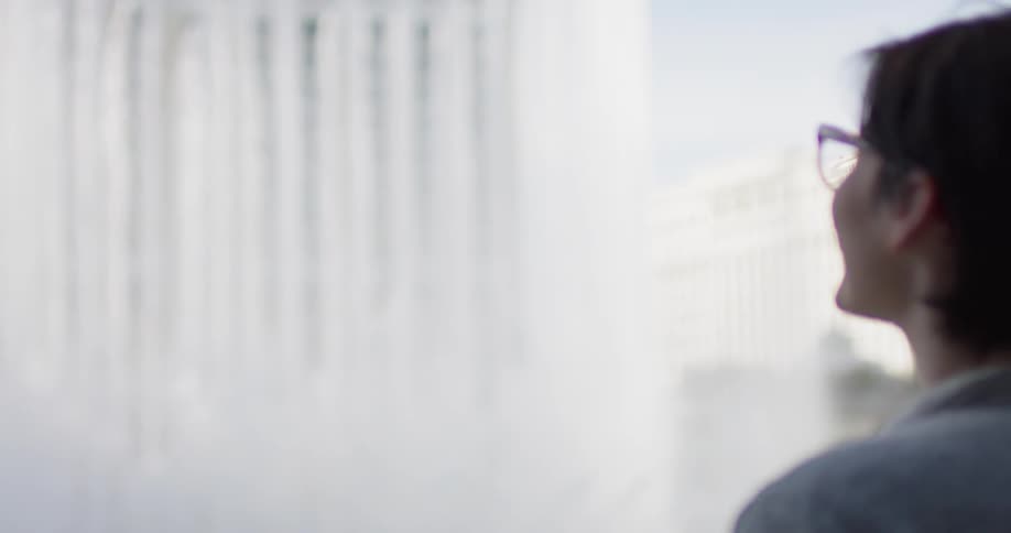 A woman is watching a fountain in the city