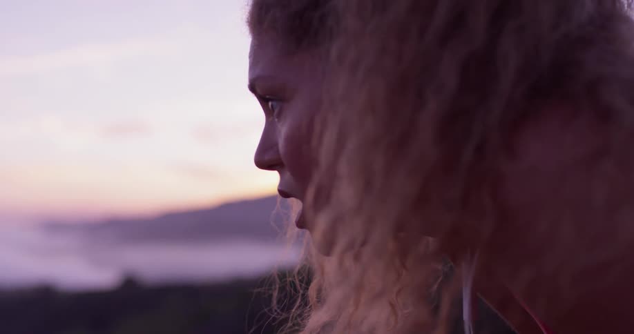 A woman leans forward by the beach at dawn