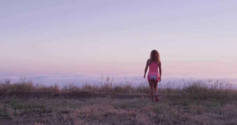 A woman walks towards the hill side