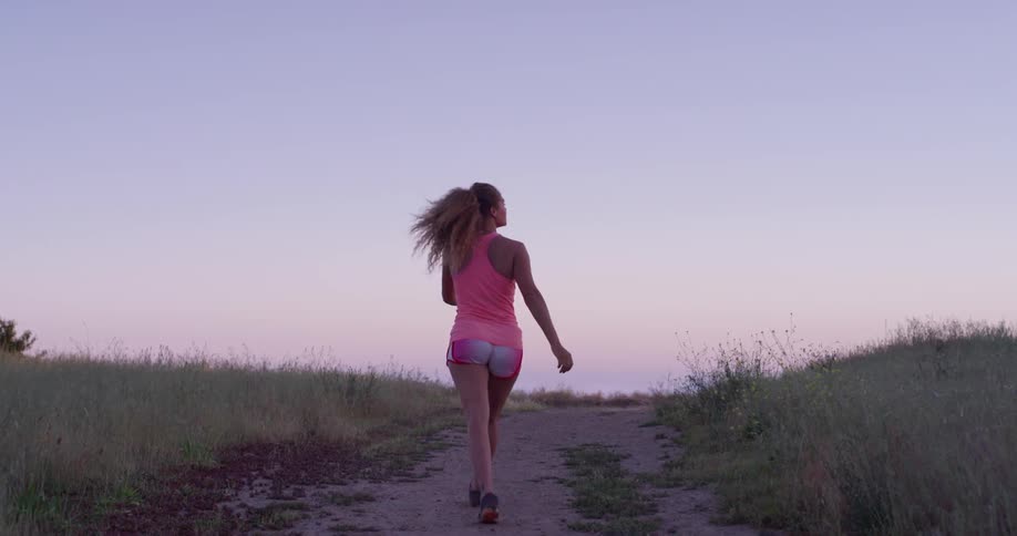 Woman is jogging on wilderness path at sunset