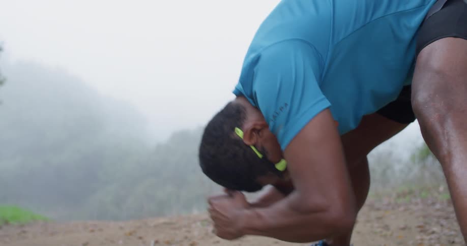 Man squats down to stretch outside on a cloudy day