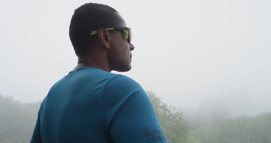 The man stands near the fog covered forest
