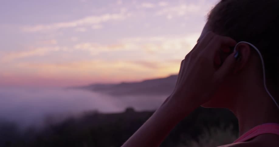 The woman takes off her ear phones as she hikes