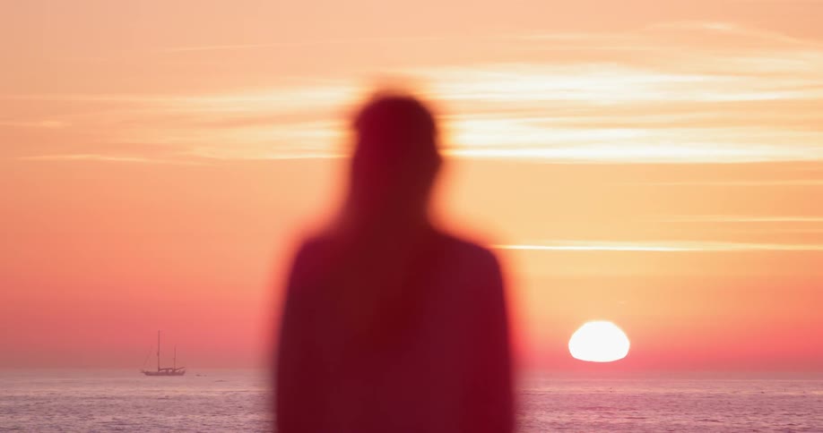 A woman watches a sunset on a beach