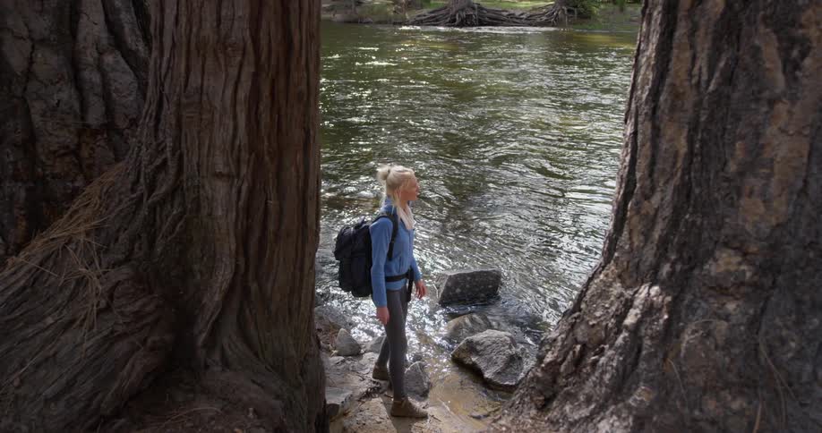 A woman walks on rocks near the river