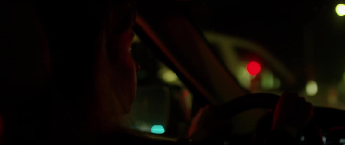 A woman drives a car in a city at night
