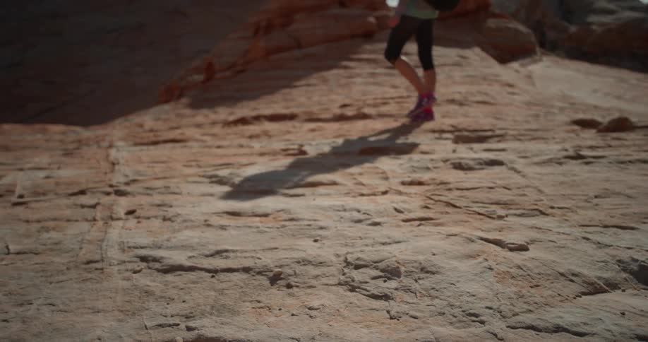 Woman walks over rocky hilly terrain