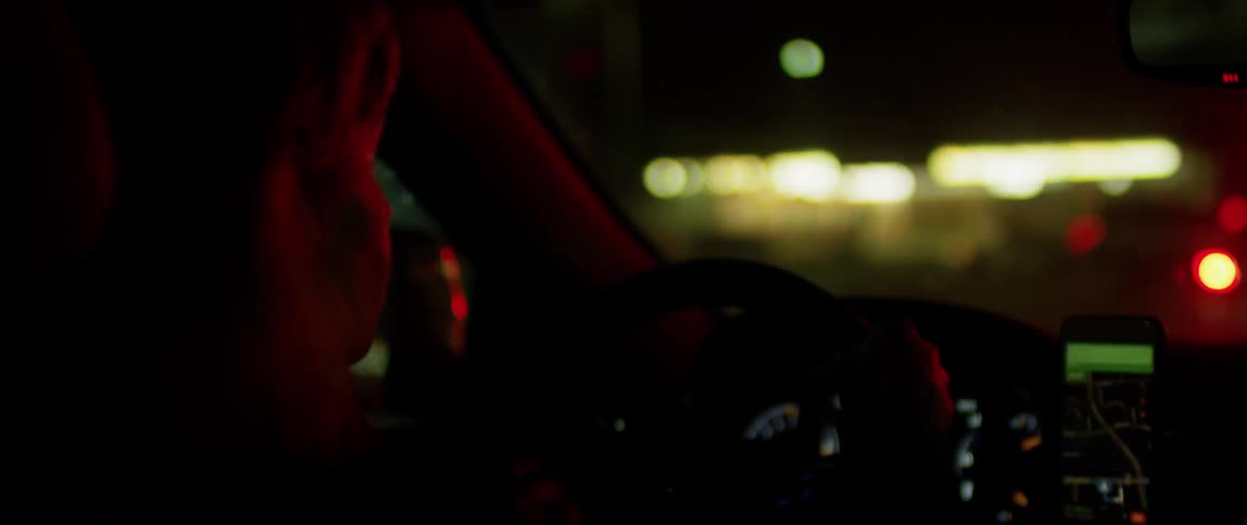 A woman is driving in town at night