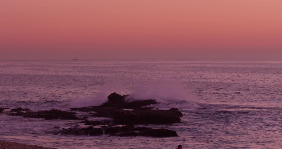 Ocean waves crash into rocks at sunset