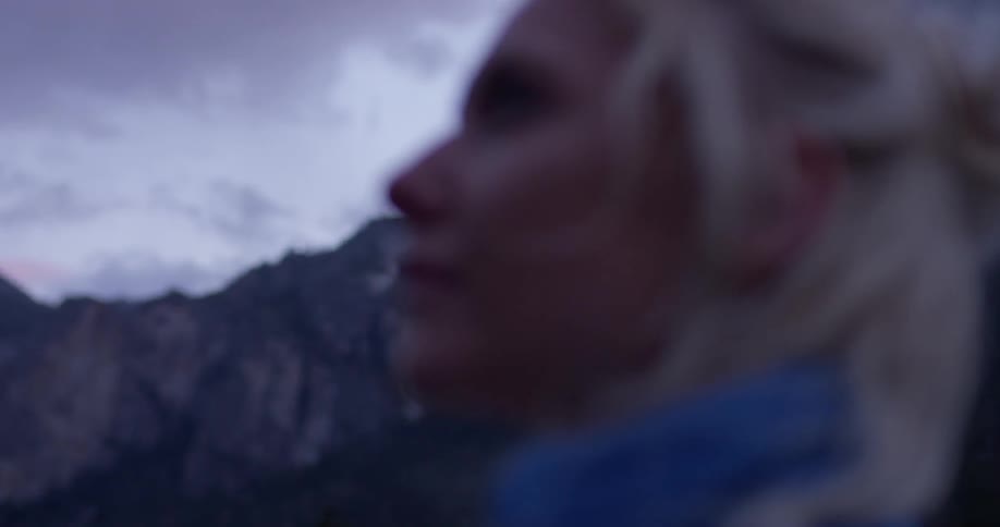 Woman looks out over rocky hilly terrain