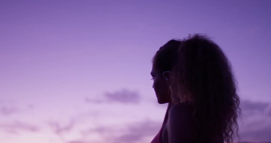 A woman puts in her ear buds and looks around outside