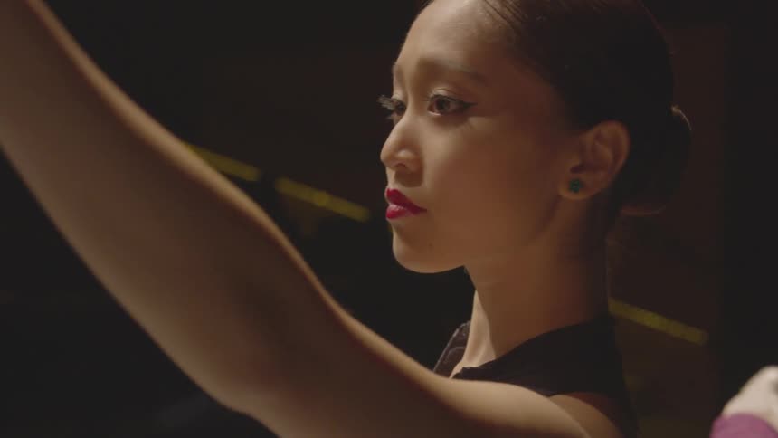A ballerina dancer stretches and lifts her left
