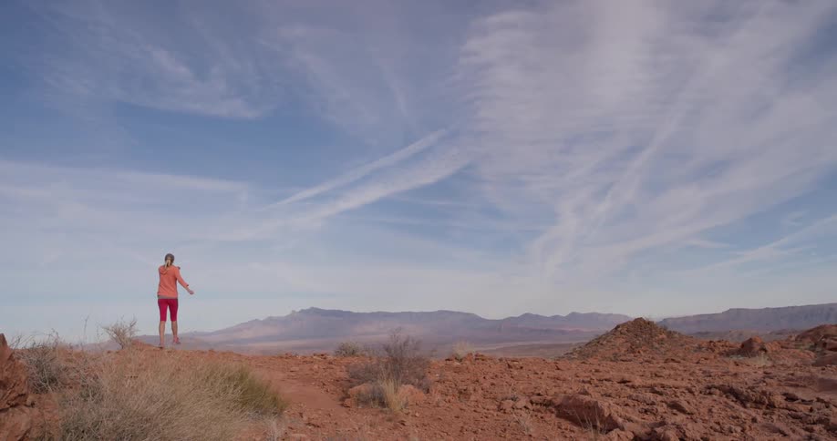 A woman jogs uphill on a cloudy day