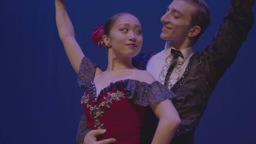 A man and woman smile at each other as they dance