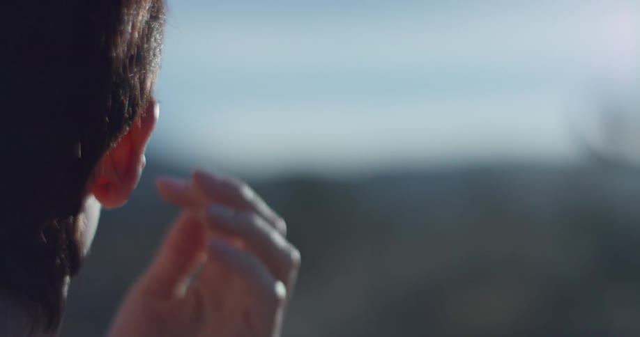 A woman takes off her sunglasses in a desert