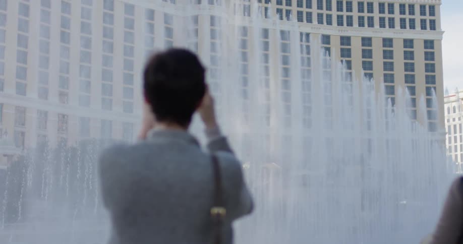 A woman takes photos of a large fountain spraying water