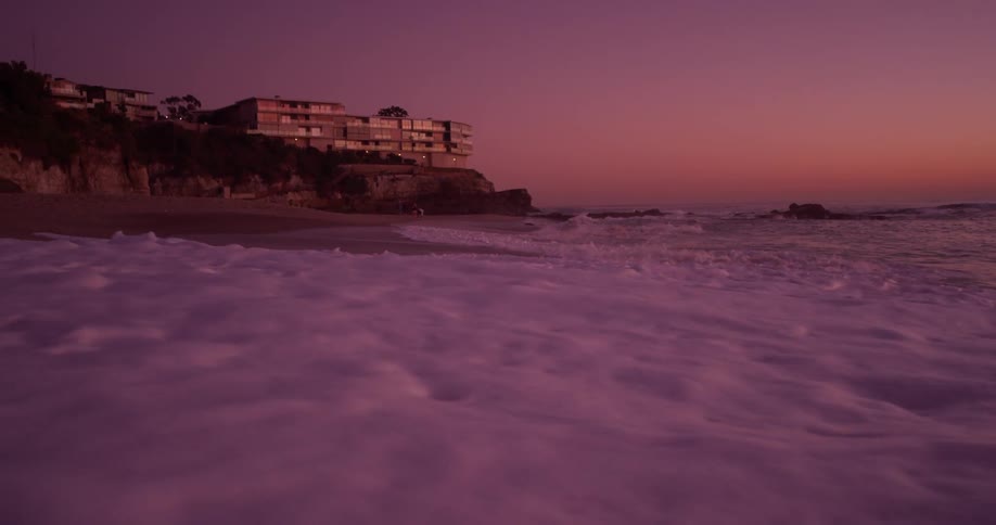 Waves crash into shore under the dark sky
