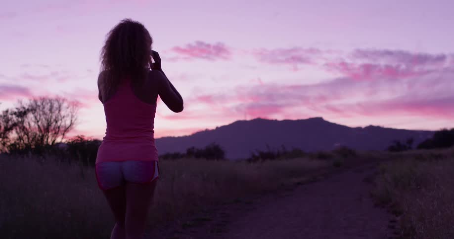 Woman walks on a path outside at sunset