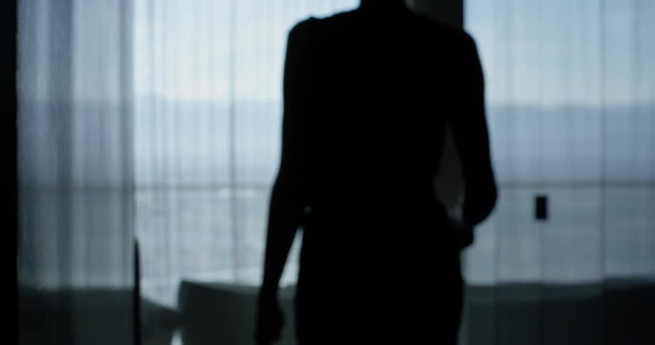 A woman walks through her home dragging luggage