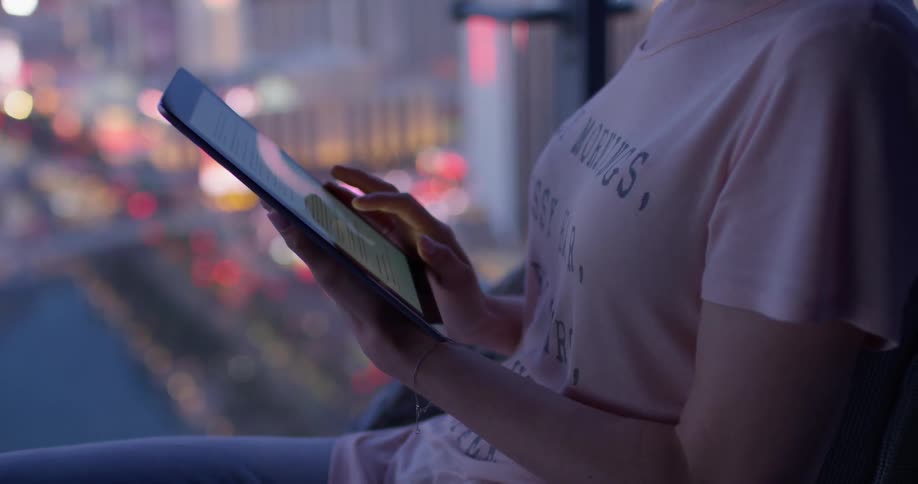 A woman is using her tablet on the balcony