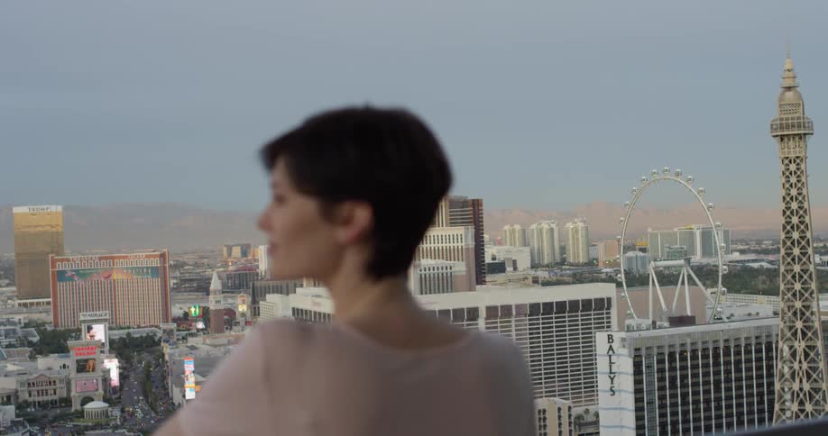 A woman looks at the tall buildings from her balcony