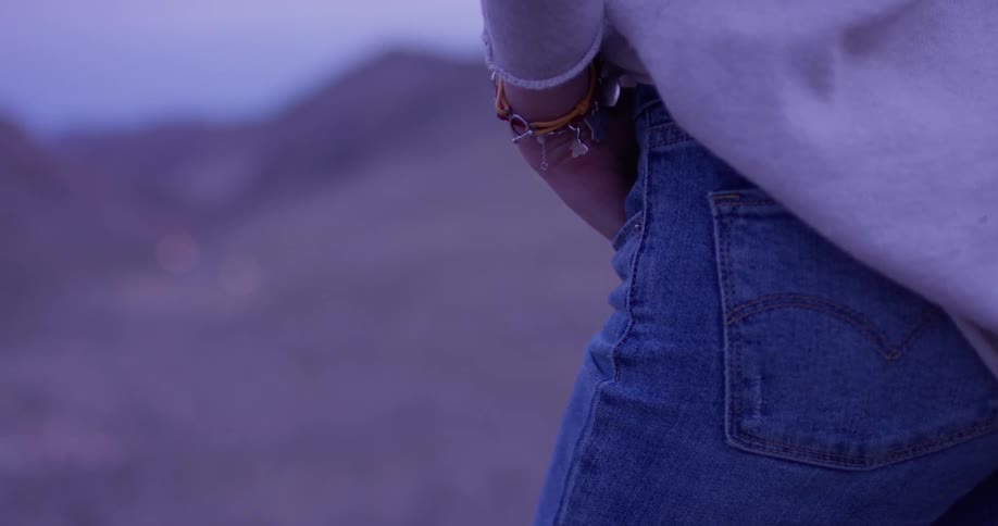 Woman wearing jeans and a bracelet stands with her hand in her pocket
